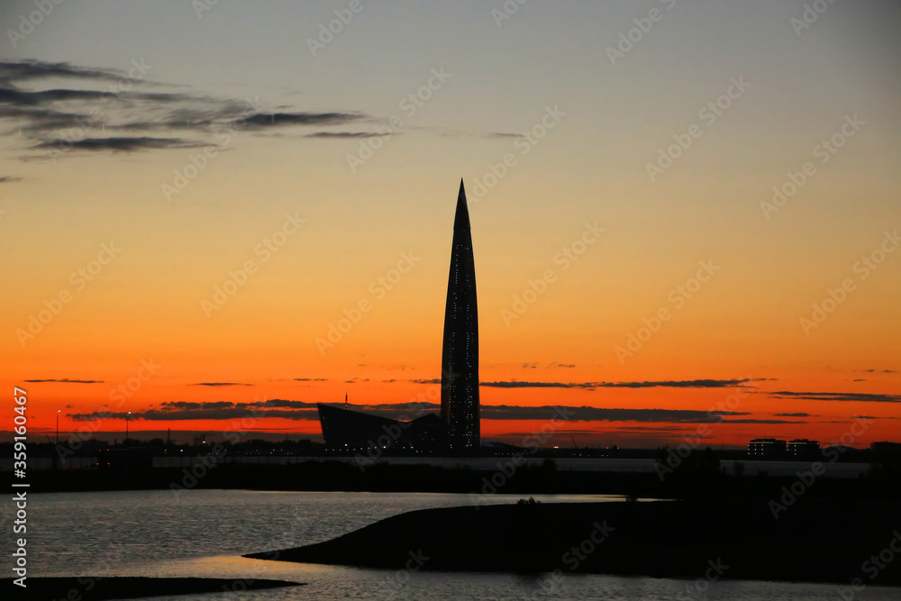 Fototapeta premium Silhouette of the skyline of the city at sunset with the Lakhta Center skyscraper, in the northwestern neighborhood of Lakhta in Saint Petersburg, Russia.