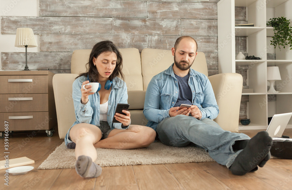 Holding coffee and smartphone while relaxing in living room floor. Holding coffee and smartphone while relaxing in living room floor.