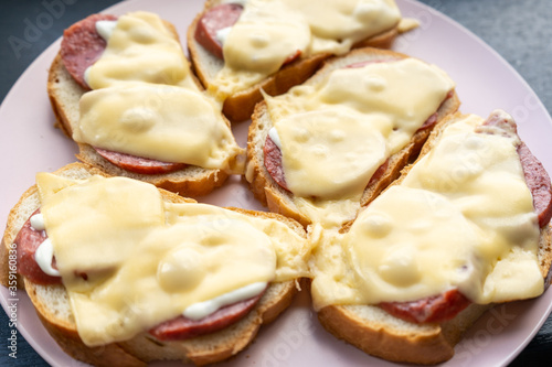Homemade hot sandwiches with sausage and melted cheese for breakfast in the morning. Close-up. 