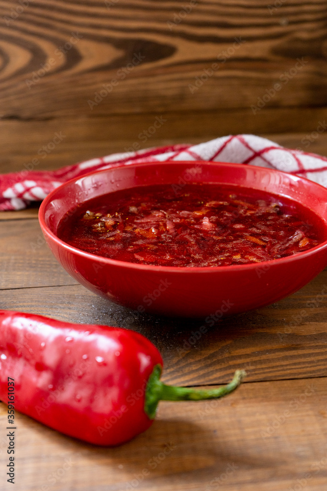 Ukrainian beetroot red hot borsch with red pepper on a brown wooden table. Top-side view Ukrainian beetroot red hot borsch with red pepper on a brown wooden table. Top-side view