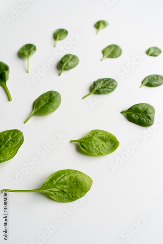 Fresh green spinach leaves on a white table. Healthy vegetable diet food. Vertical. Top view. 