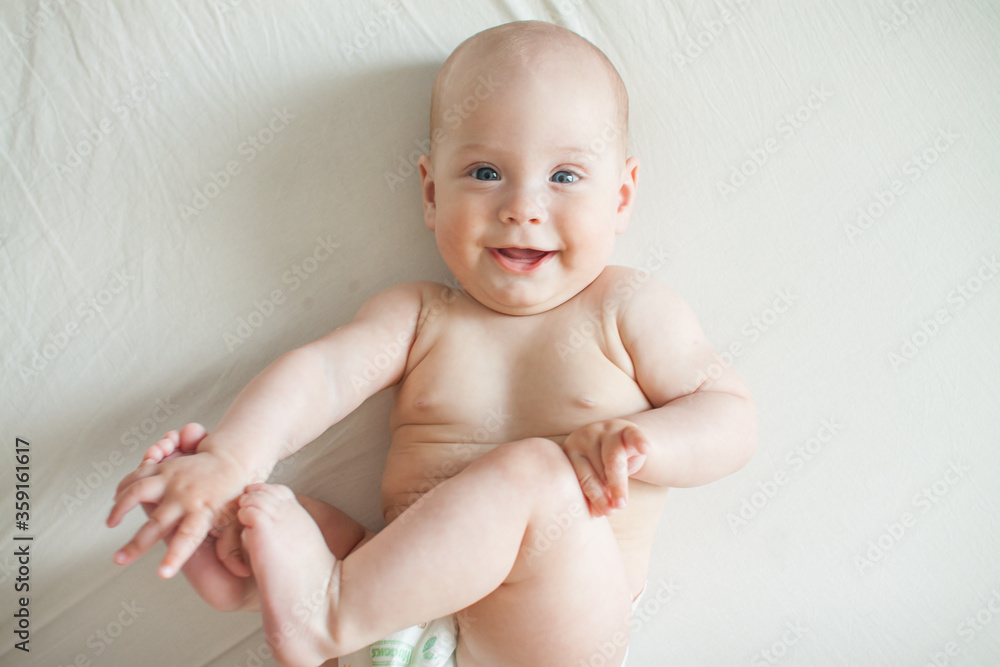 Cute baby lies on a white sheet and plays fun Cute baby lies on a white sheet and plays fun