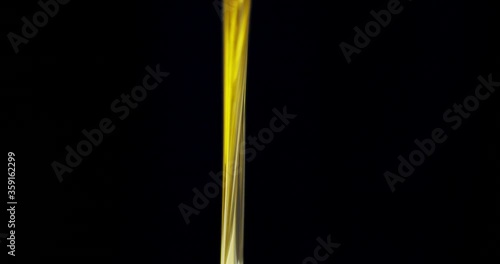 Stream olive oil pouring. On a black background.