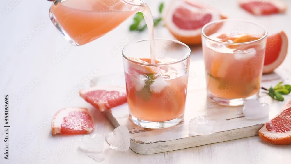 Grapefruit cocktails with mint and ice. Cold summer citrus fresh beverage on light wooden background Grapefruit cocktails with mint and ice. Cold summer citrus fresh beverage on light wooden background