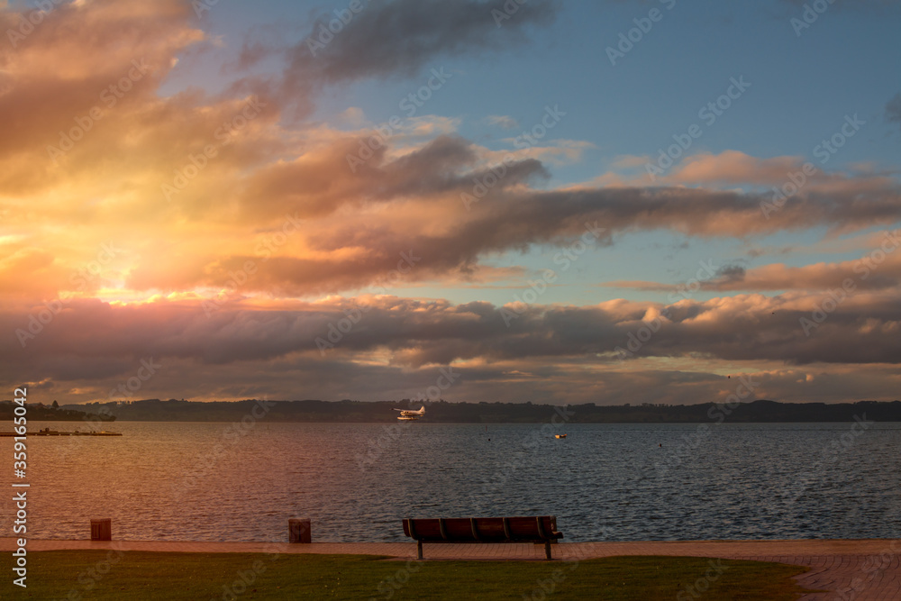 A hydroplane taking off from lake Rotorua towards dramatic sunset