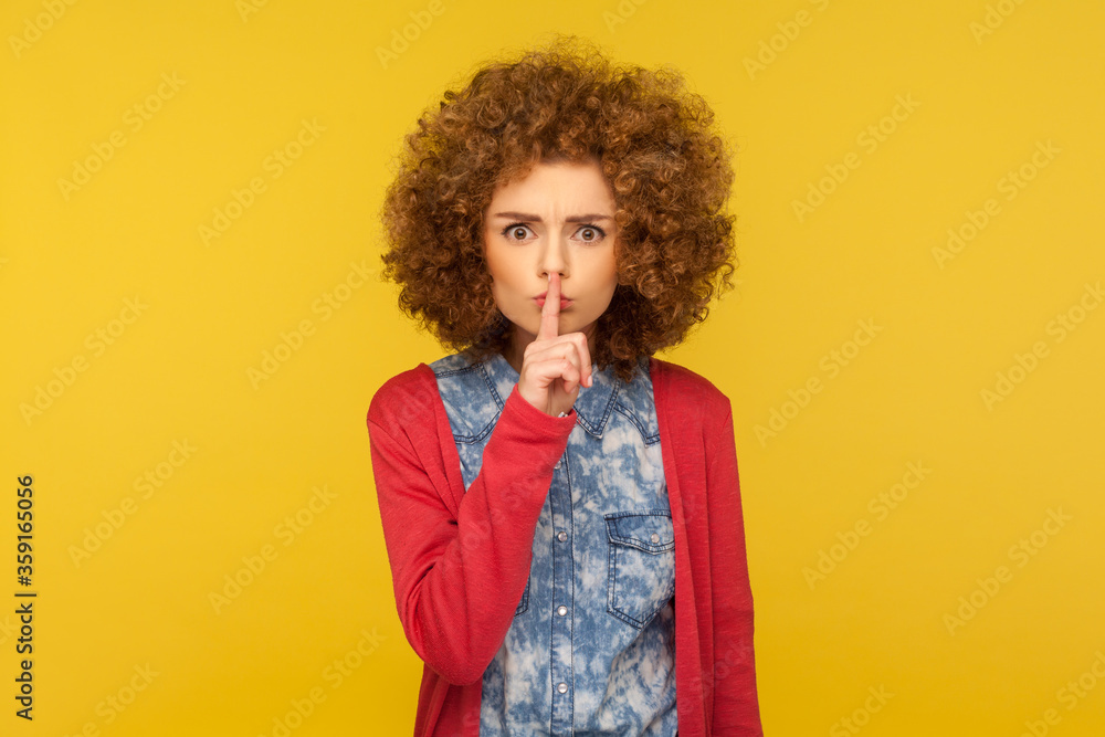 Shut up, don't speak! Portrait of serious displeased woman with curly hair shushing, holding finger on lips, asking to keep silence, forbidden to talk. indoor studio shot isolated on yellow background Shut up, don't speak! Portrait of serious displeased woman with curly hair shushing, holding finger on lips, asking to keep silence, forbidden to talk. indoor studio shot isolated on yellow background