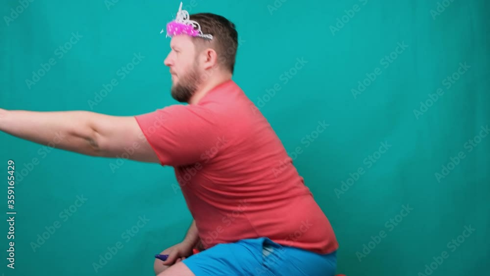 handsome bearded freaky man in a pink T-shirt with a diadem on his head is riding astride a unicorn with a magic wand in his hand. A funny wizard joke to make and fulfill a wish. handsome bearded freaky man in a pink T-shirt with a diadem on his head is riding astride a unicorn with a magic wand in his hand. A funny wizard joke to make and fulfill a wish.