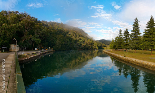Beautiful morning view of Cockle creek with reflection blue light cloudy sky, mountains and trees, Bobbin Head, Ku-ring-gai Chase National Park, New South Wales, Australia 