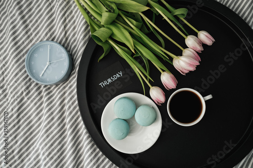 Top View of Note  Thursday  on Tray with French Macarons and Fresh Tulips with Cup of Coffee and Alarm Clock