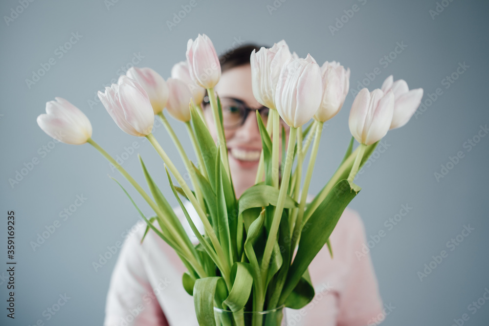 Studio Portrait of Young Adult Pretty Girl with Glasses Dressed in Pink T-shirt Holds Bouquet of Fresh Tulips Studio Portrait of Young Adult Pretty Girl with Glasses Dressed in Pink T-shirt Holds Bouquet of Fresh Tulips