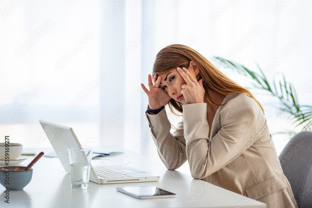 Depressed businesswoman rubbing eyes in office. Portrait of depressed young businesswoman sitting at computer in office rubbing eyes. Overworking concept Depressed businesswoman rubbing eyes in office. Portrait of depressed young businesswoman sitting at computer in office rubbing eyes. Overworking concept