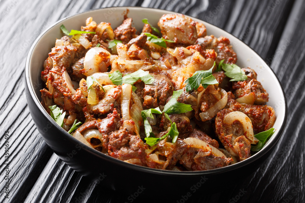 Fried chicken liver, heart and stomachs with onions, tomatoes and spices close-up in a bowl on the table. horizontal