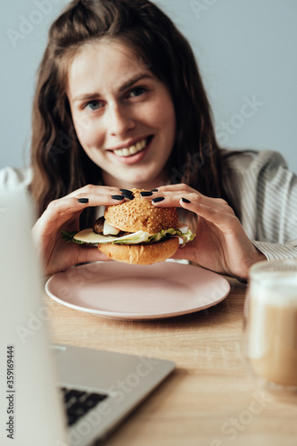 Portrait of Young Adult Girl Working From Home Eating Burger and Drink Dalgona Coffee , Freelance and Remote Work Concept