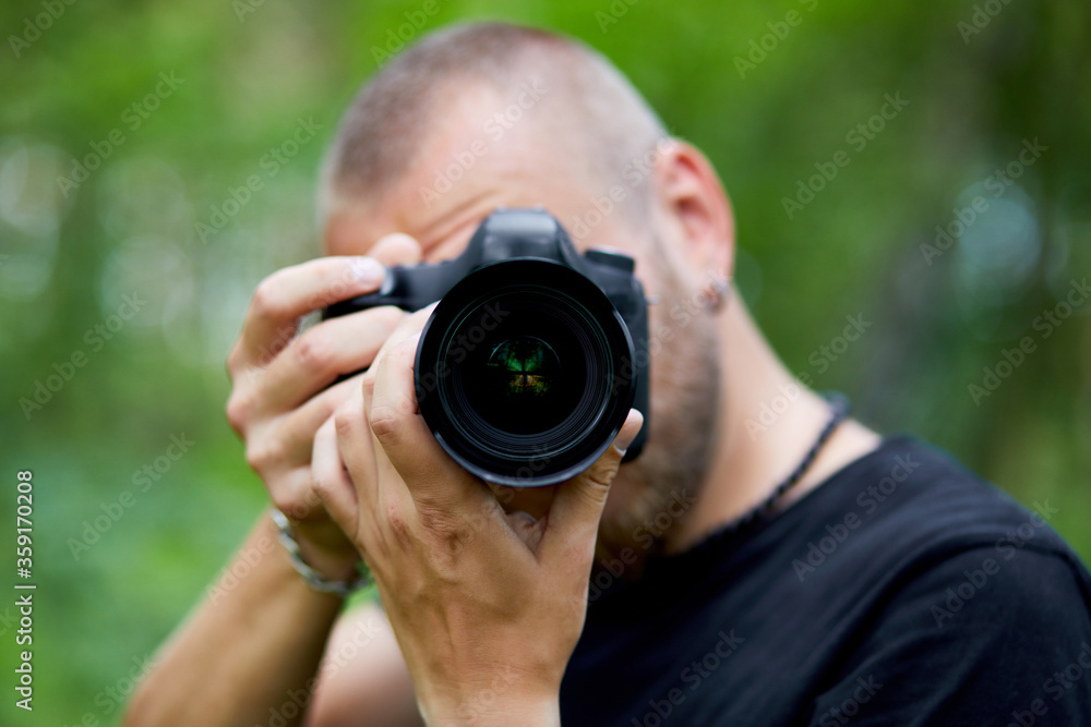 Portrait of a male photographer covering her face with the camera