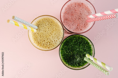 Flat Lay of Three Different Colored Smoothie Cocktails on Pink Background