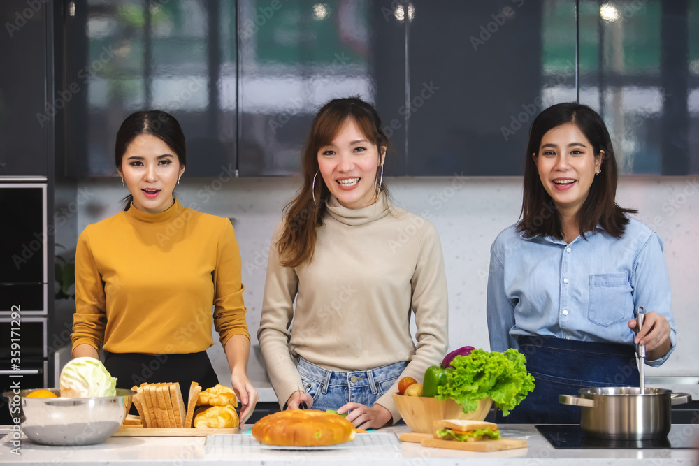 Naklejka premium Three asian beautiful woman standing cooking food in the kitchen,