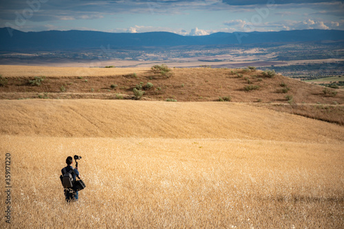 young filmmaker filming natural landscape in canyon with a large river and marshes