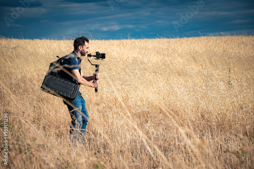 young filmmaker filming natural landscape in canyon with a large river and marshes