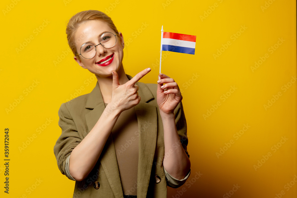 Style blonde woman in jacket with Dutch flag on yellow background