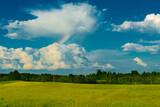 Beautiful landscape green meadow against blue sky and rainbow.