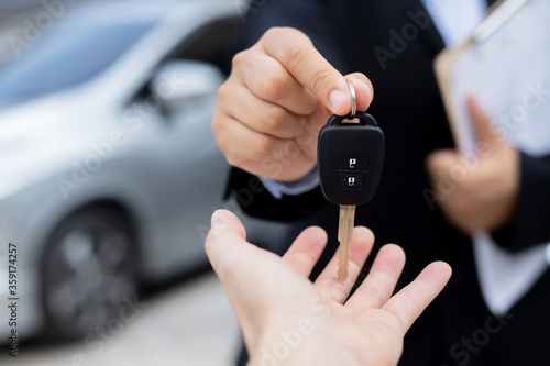 The staff holds the new car keys and offers special interest promotions to customers at the showroom.
