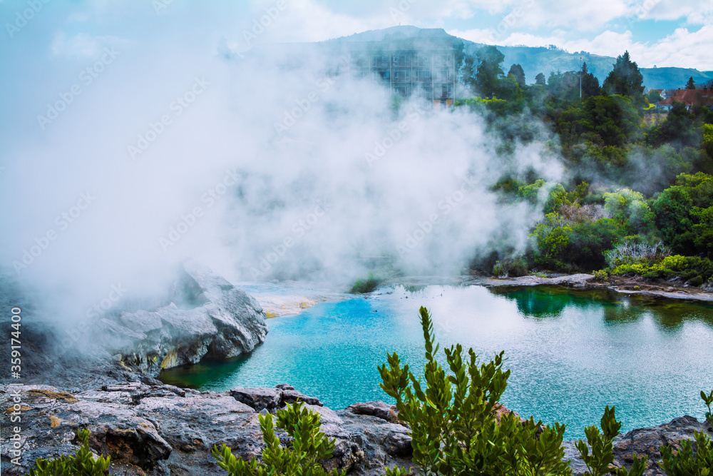 Thick steam hovering over turquoise water of a geothermal pool in the mountains