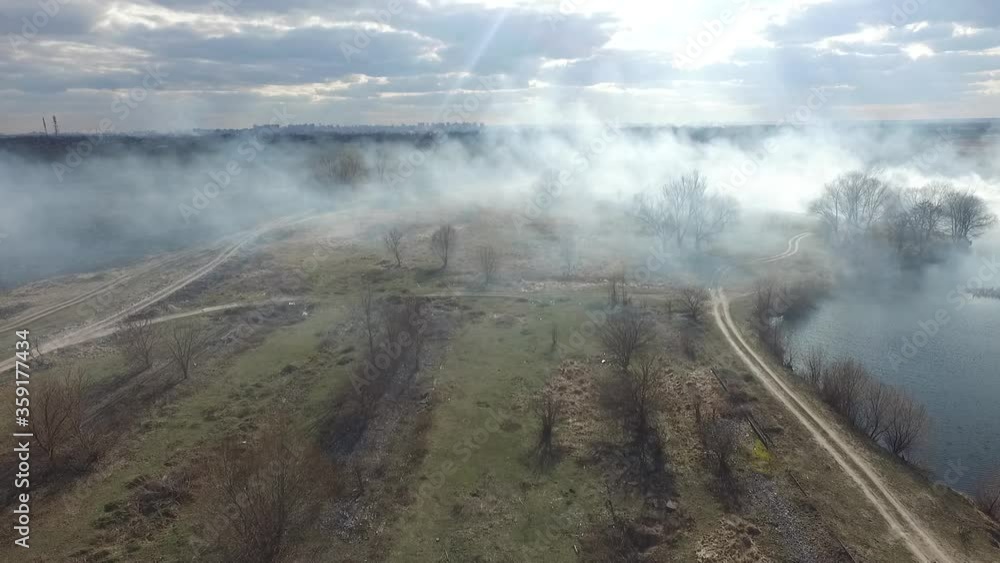 The smoke from the burning of dry grass (drone image).Local residents set fire to the grass specifically. Small animals are bending. Local features and habits. Near Kiev,Ukraine The smoke from the burning of dry grass (drone image).Local residents set fire to the grass specifically. Small animals are bending. Local features and habits. Near Kiev,Ukraine