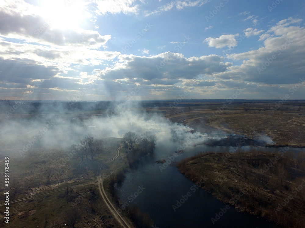 The smoke from the burning of dry grass (drone image).Local residents set fire to the grass specifically. Small animals are bending. Local features and habits.  Near Kiev,Ukraine