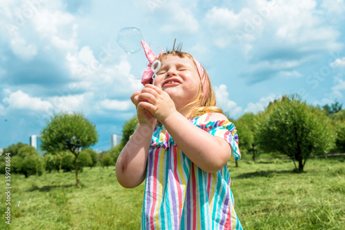 Cute little girl is blowing a soap bubbles.Fashionable baby girl in outdoors park, active games, runs © irishasel