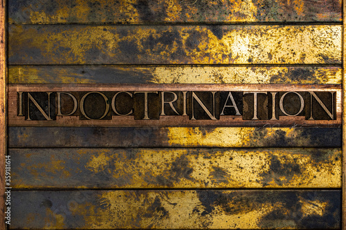 Indoctrination text formed with real authentic typeset letters on vintage textured silver grunge copper and gold background photo