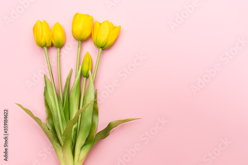 Fototapeta Naklejka Na Ścianę i Meble -  Yellow tulip flowers bouquet on pink background. Flat lay, top view. Minimal floral concept. Spring flowers, floral background