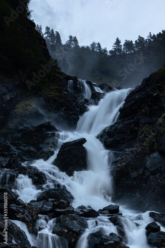 Latefossen Waterfall  unique waterfall epic powerful main silky flow vertical photo in dark light with long exposure. Twin waterfall in the Odda valley  Norway