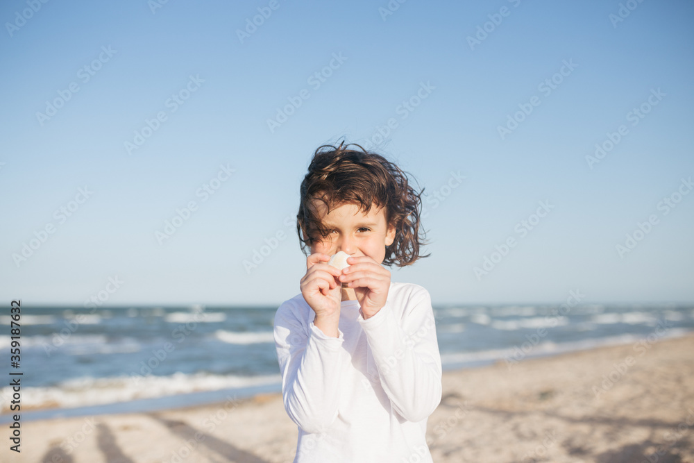 Little cute girl searching seashells on the sea beach