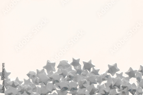 Light background of white matte paper stars located on bottom and an empty place for text.
