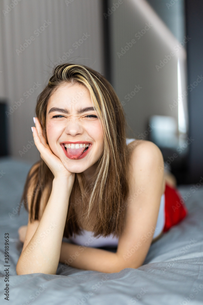 Portrait pretty young girl make faces on bed in modern apartment in the morning. Portrait pretty young girl make faces on bed in modern apartment in the morning.