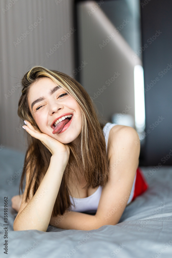 Portrait pretty young girl make faces on bed in modern apartment in the morning. Portrait pretty young girl make faces on bed in modern apartment in the morning.