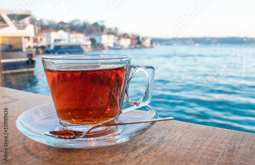 A cup of Turkish tea against the background of the cruise ship. Turkish tea served in the typical manner. Turkish tea in mug cup. Bosphorus