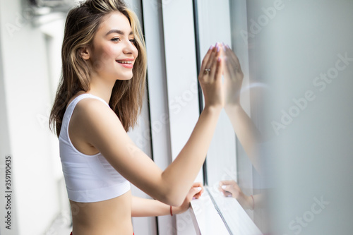 Young smiling woman relaxing at cozy home, feeling happy, resting in the morning, looking through the window