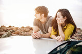 young couple by a sports car parked on the beach. Romance and love in a car trip