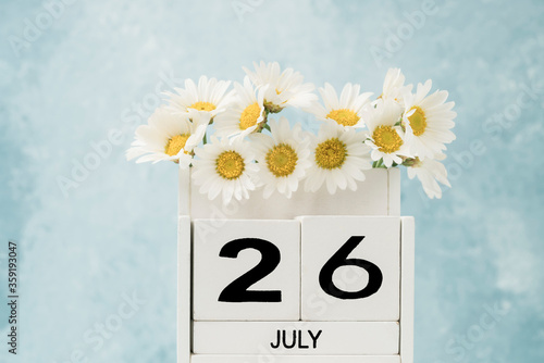White cube calendar for july decorated with daisy flowers with copy space photo