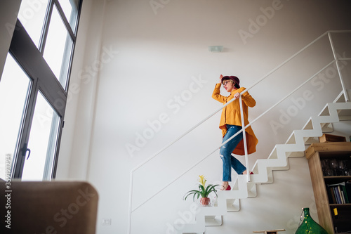 Adult woman going downstairs at home - Lovely woman cheerful on staircase photo