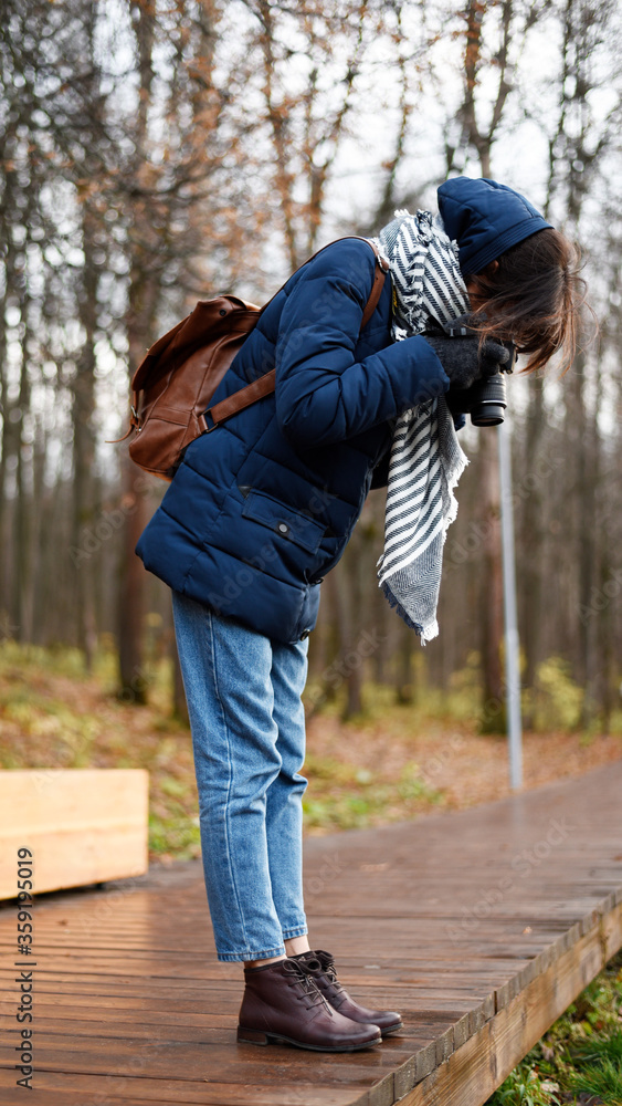 Young woman absorbedly taking photos in forest of something on the ground Young woman absorbedly taking photos in forest of something on the ground