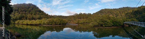 Beautiful morning view of Cockle creek with reflections of blue sky, foggy mountains and trees, Bobbin Head, Ku-ring-gai Chase National Park, New South Wales, Australia