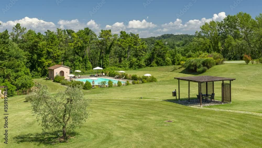 Aerial view of a swimming pool surrounded by the greenery of Tuscany, Italy, with movement of clouds in time lapse Aerial view of a swimming pool surrounded by the greenery of Tuscany, Italy, with movement of clouds in time lapse