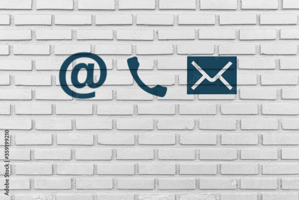 Contact Us. Phone, email and post icons paint on white brick wall Contact Us. Phone, email and post icons paint on white brick wall