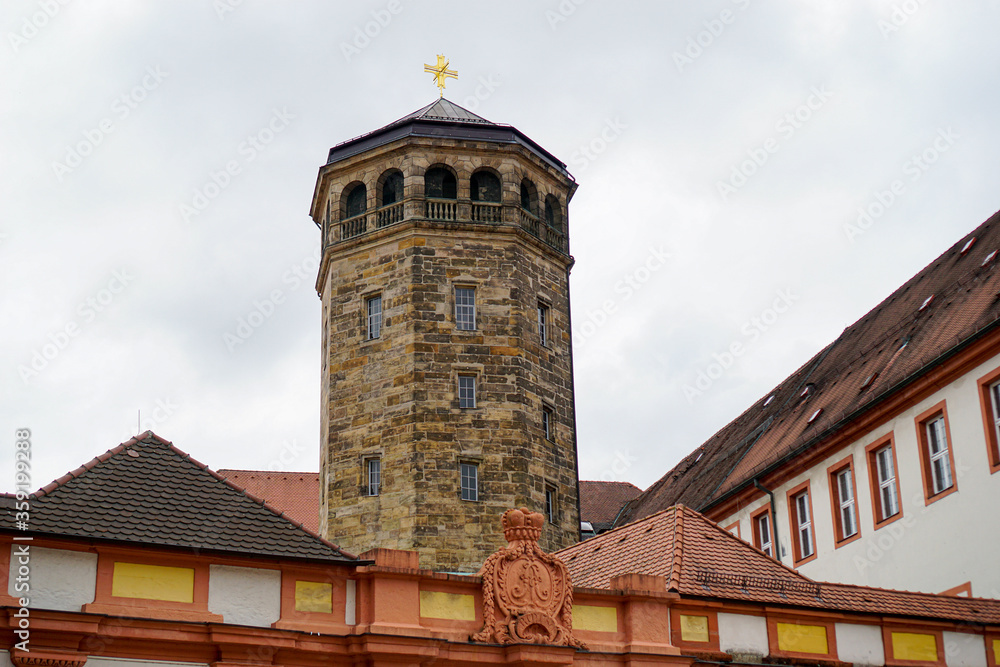Fototapeta premium Schlossturm aus Sandstein mit Balkon und Schieferdach und goldenem Kreuz auf der Spitze. Schlossfassade im Vordergrund. Altes Schloss Bayreuth in Bayern, Deutschland.