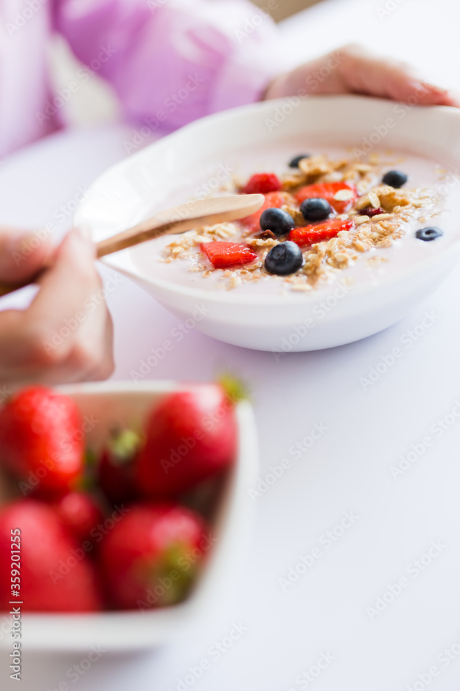 Woman eating fresh muesli with milk and fruits at the table. Woman eating fresh muesli with milk and fruits at the table.