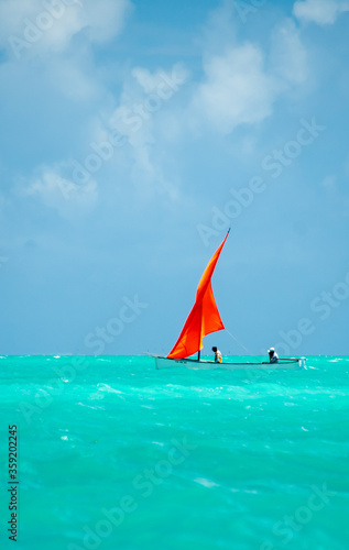 Sail boats in the lagoon of Rodrigues island. Traditional pirogues with bright orange sails