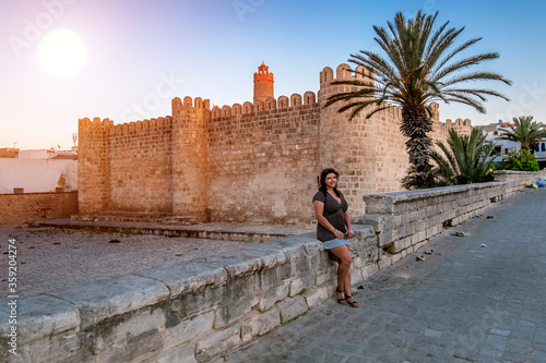 A girl posing against the backdrop of the Ribat fortress at sunset in Sousse.