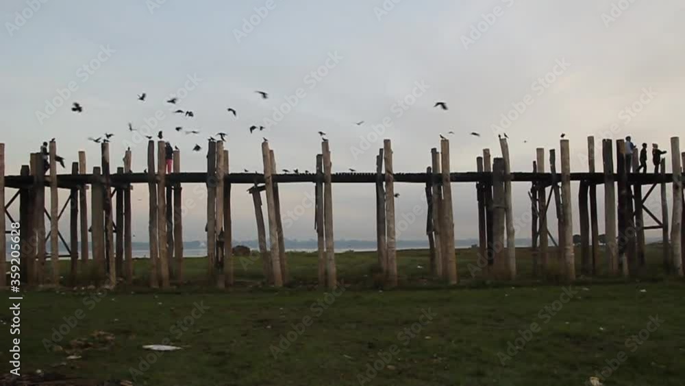 MANDALAY, MYANMAR - DECEMBER 4, 2016: Buddhist monks are crossing U Bein bridge over Taungthaman lake in Amarapura near Mandalay, Myanmar MANDALAY, MYANMAR - DECEMBER 4, 2016: Buddhist monks are crossing U Bein bridge over Taungthaman lake in Amarapura near Mandalay, Myanmar